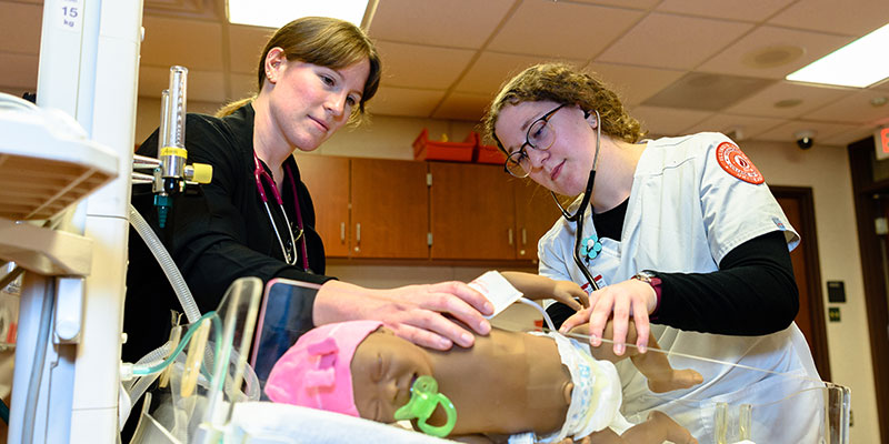 A student getting trained with examining a baby.